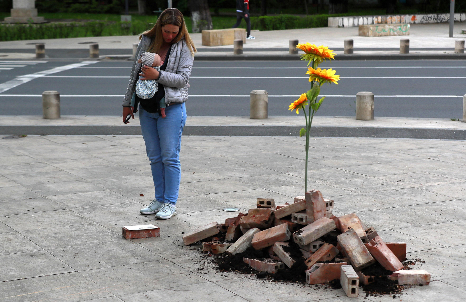 Una madre observa un homenaje a los caídos de Ucrania en una calle de Bucarest (Rumanía).
