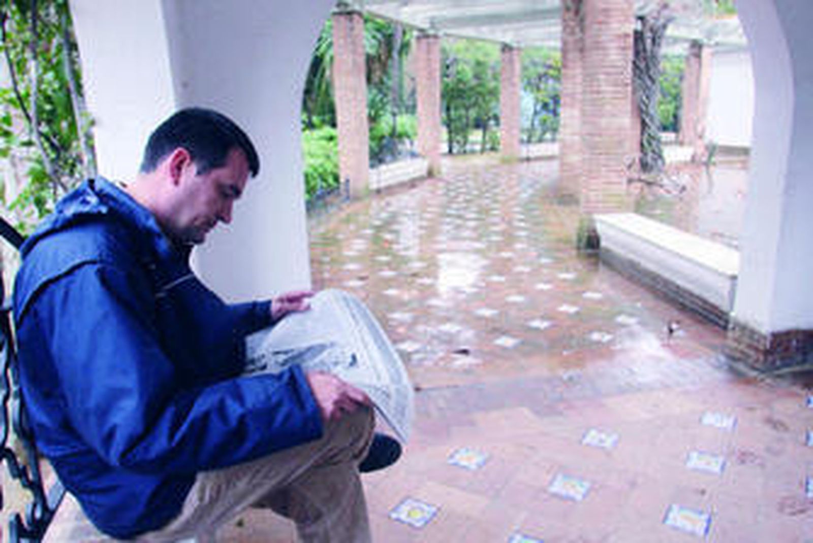 Un paseante lee el periódico en el Parque de María Luisa.