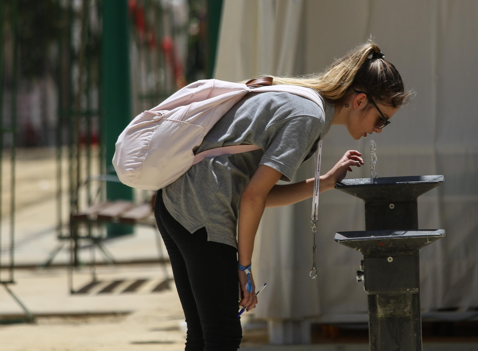 Una joven se refresca en una fuente en Granada.