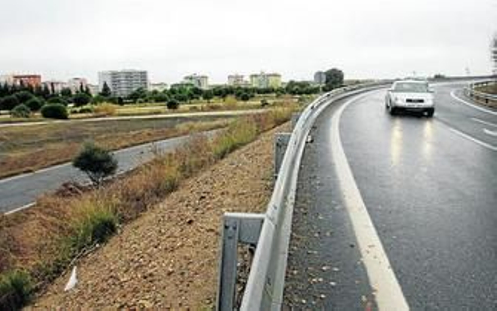 Un vehículo transita con las luces encendidas por un tramo de carretera cercano a los terrenos del Parque del Tamarguillo.