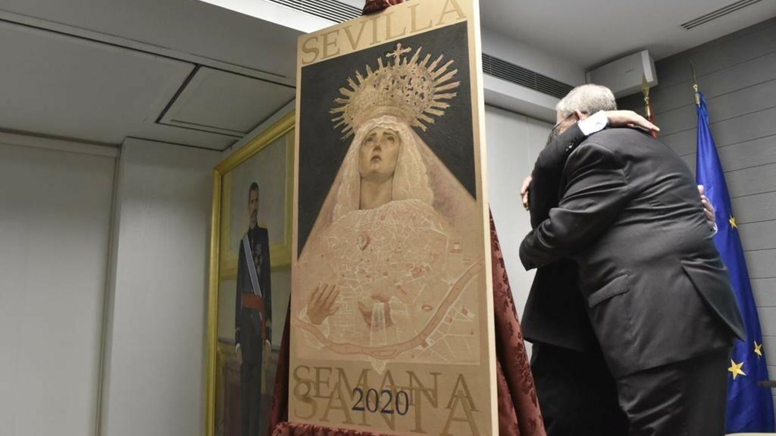 El presidente del Consejo y el cartelista se abrazan tras descubrirse la obra.