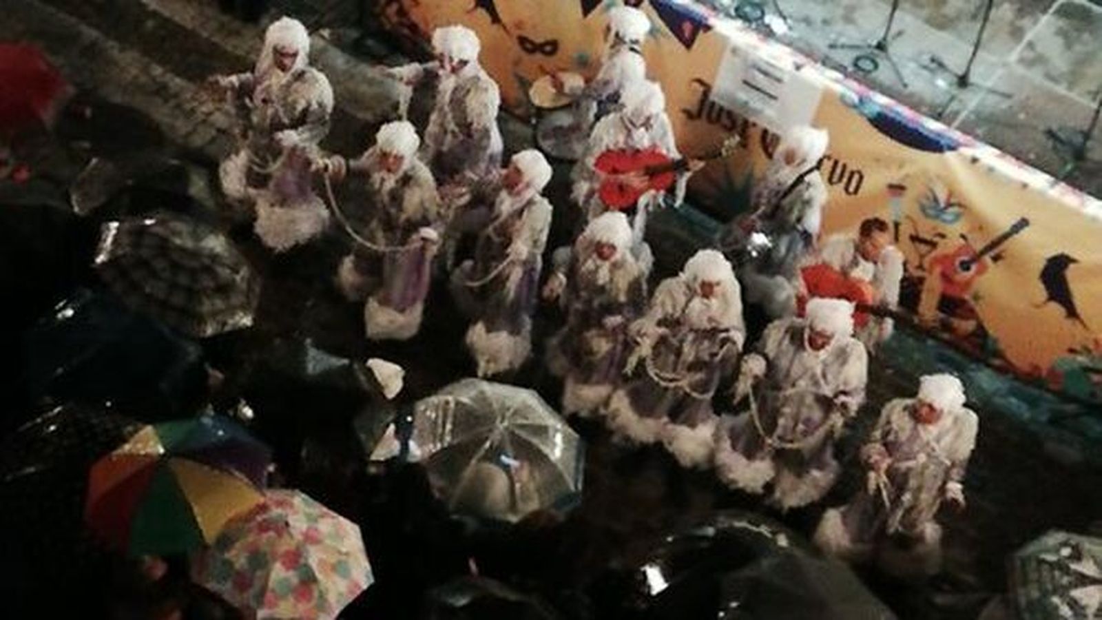 Los aficionados protegidos bajo paraguas escuchando a Los mi alma en la Viña.