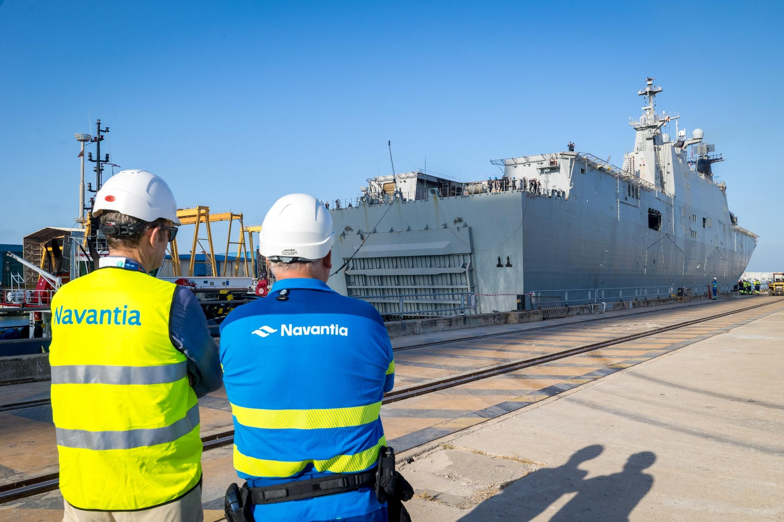 Dos responsables de Navantia observan la maniobra de entrada del buque 'Juan Carlos I' en el astillero de Puerto Real.