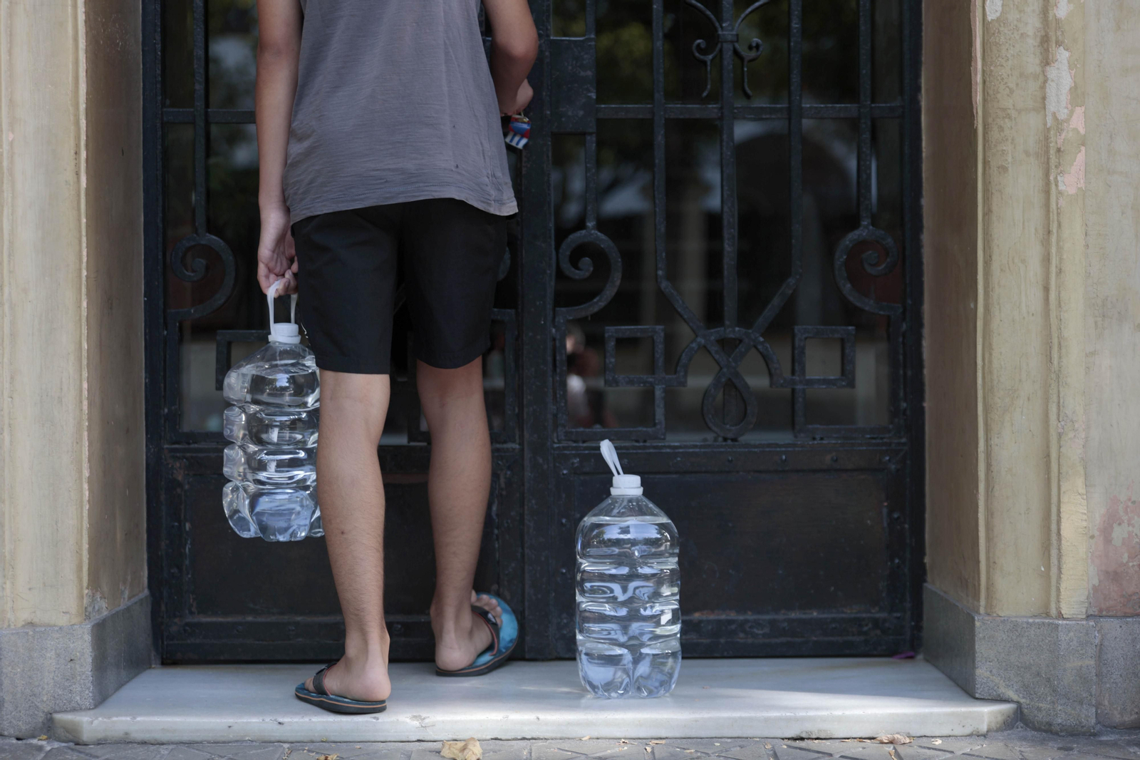 Un vecino porta dos botellas de agua en previsión a las restricciones durante la noche