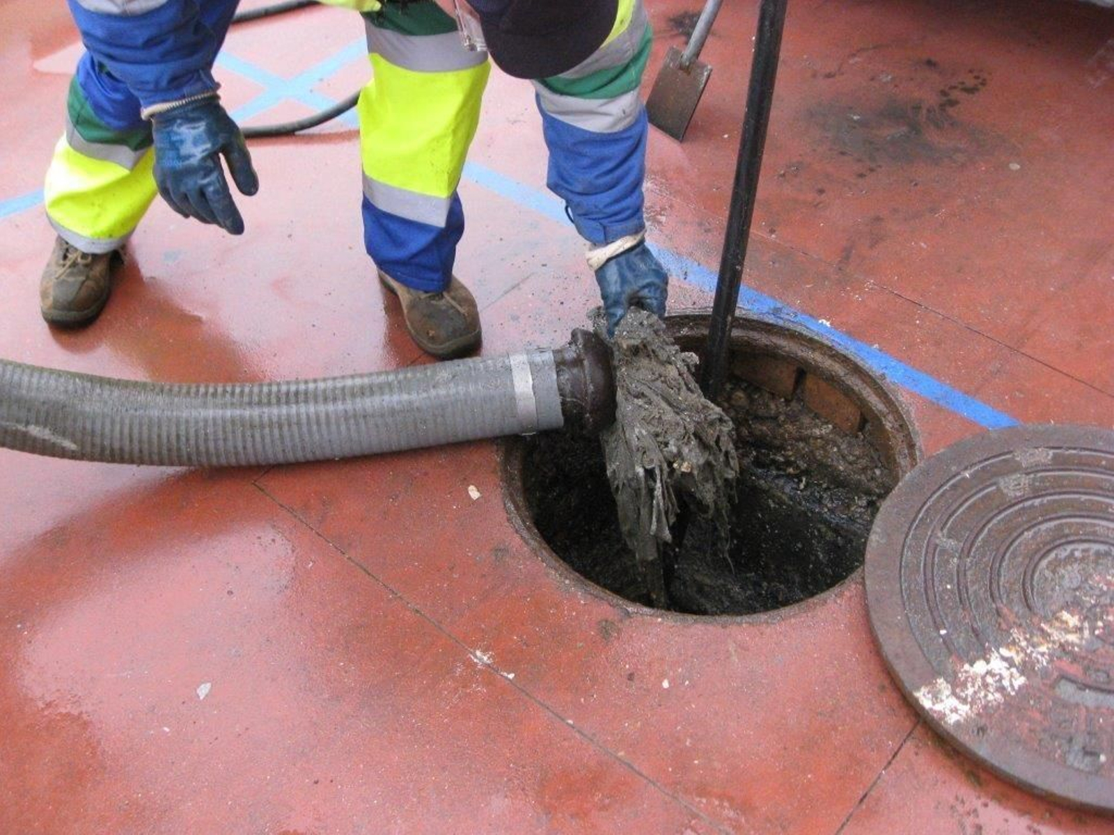 Operarios quitan toallitas del alcantarillado.