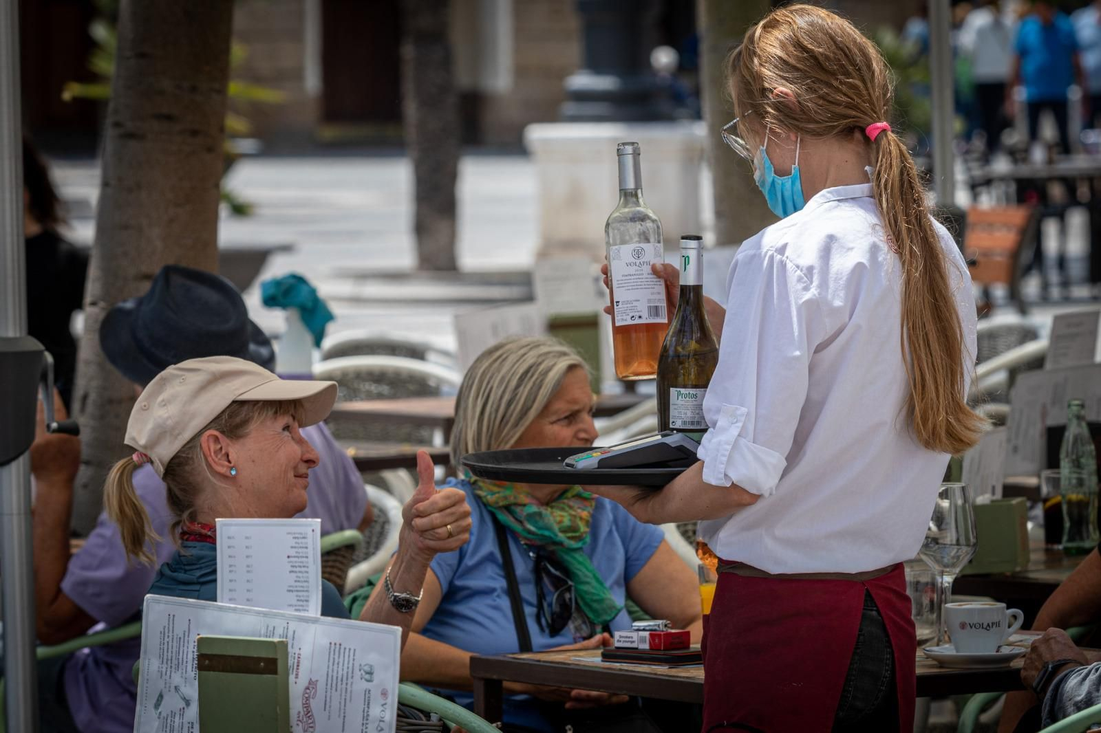 Una camarera atiende a unos clientes en una terraza en el centro de Cádiz.
