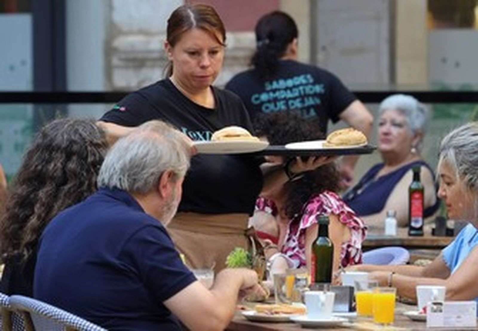 Una camarera sirviendo el desayuno a un par de personas.