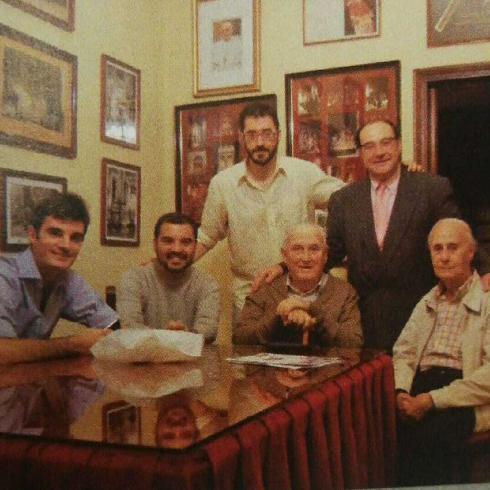 Fotografía en la casa de hermandad. Juan Carlos Valverde aparece sentado con bastón. Sentado a su izquierda está Eduardo Recio, censor y vestidor del Señor ya fallecido. Tras ellos está Manuel García Fernández y jóvenes de la hermandad.