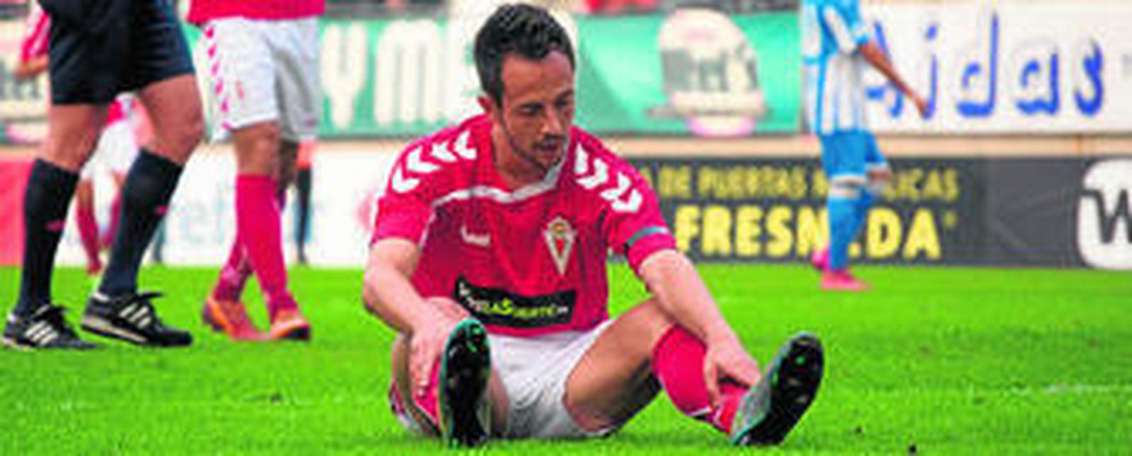 El delantero ex cadista Carlos Álvarez, ahora en las filas del Real Murcia, se muestra decepcionado mientras aparece sentado sobre el terreno de juego.