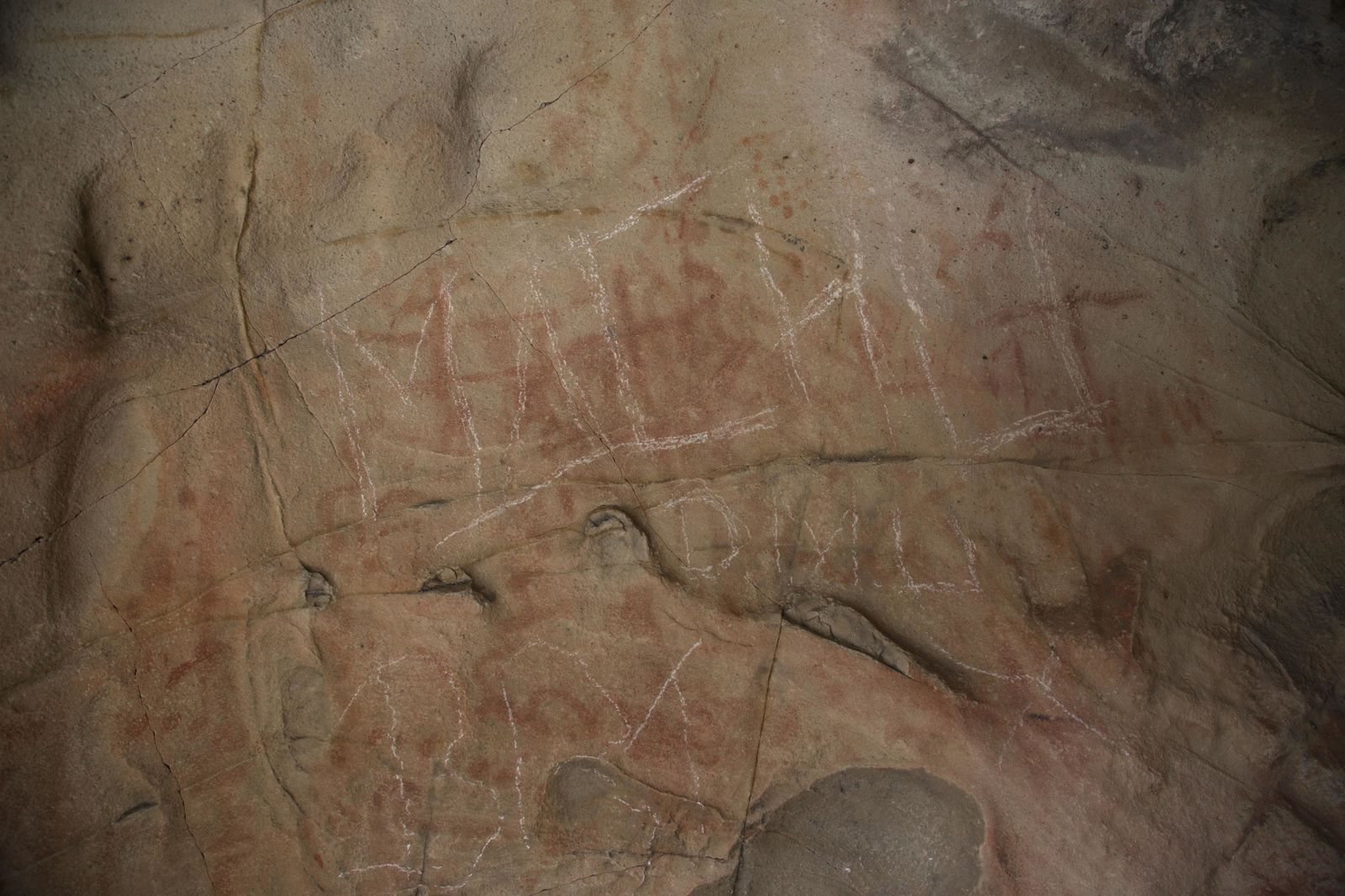 El panel principal, donde se observa los trazos blancos realizados aparentemente con una piedra arenisca sobre las pinturas rupestres.