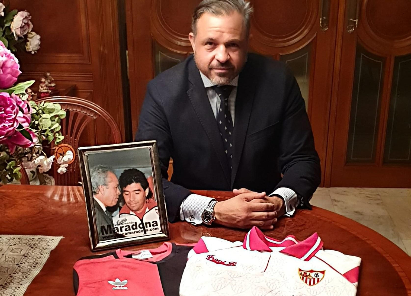Luis Cuervas posa en su casa con una foto de su padre y Maradona y las camisetas de Newells y Sevilla regalos de Diego.