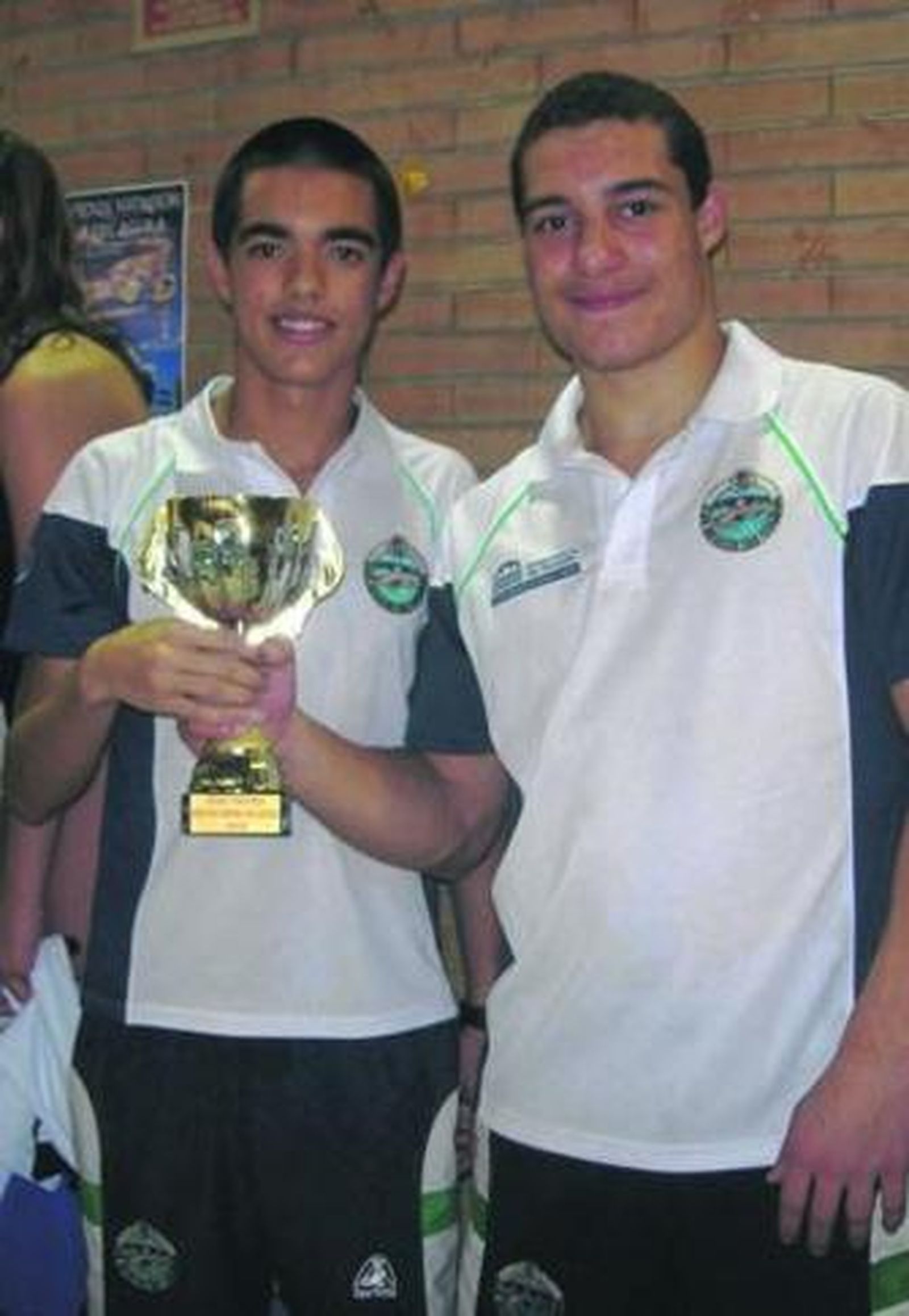 Dos componentes del equipo isleño posan con la copa conquistada.