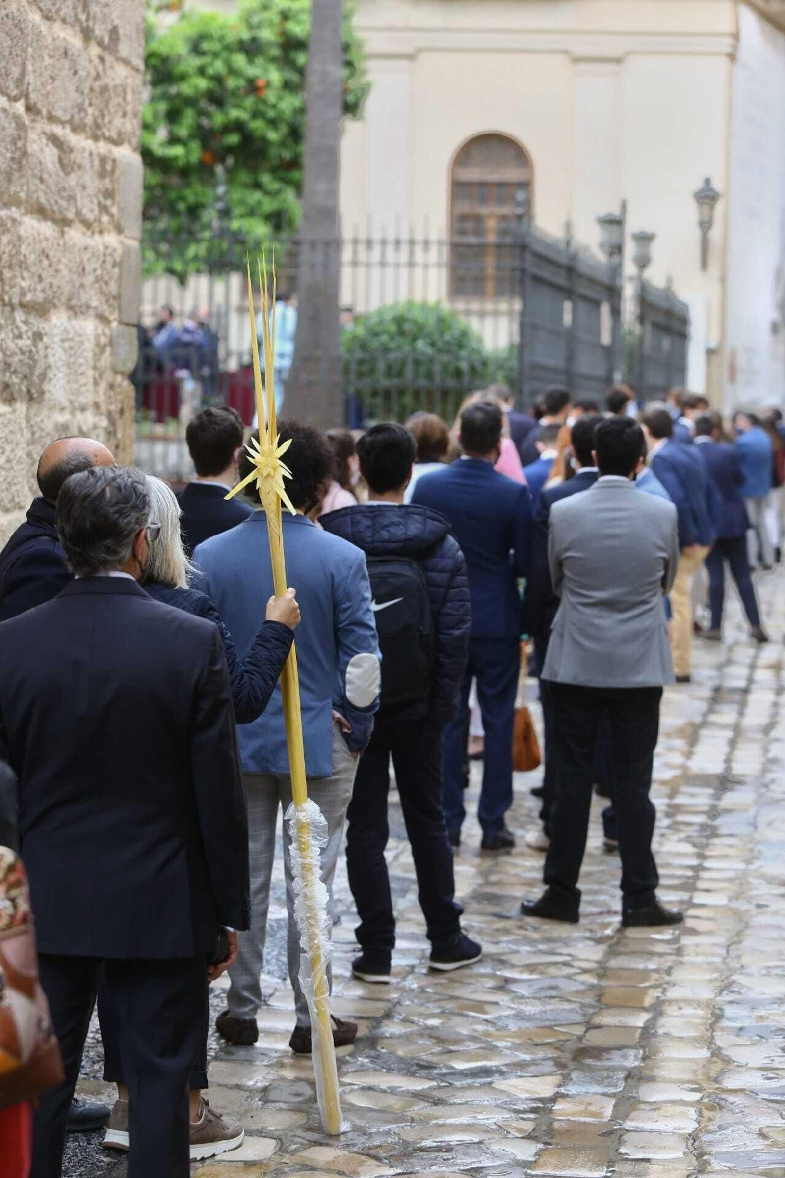 Fiel con una palma espera para acceder al templo.