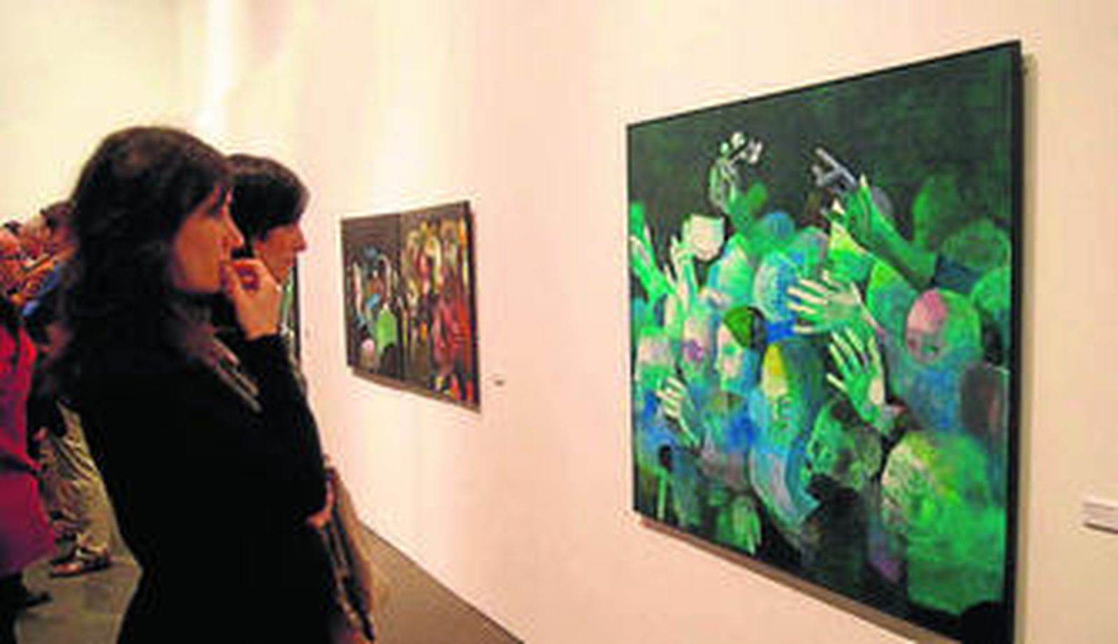 Dos jóvenes contemplan una obra de la pintora Teresa Peña.