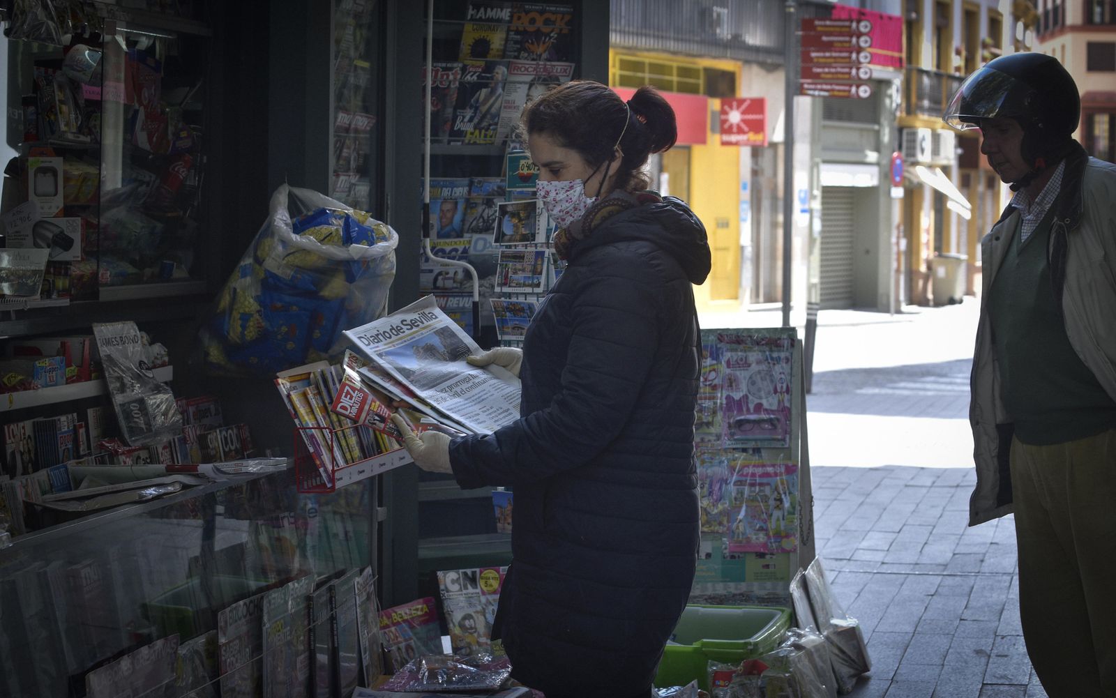 Una mujer realiza una compra en uno de los pocos quioscos que siguen abiertos en Sevilla.