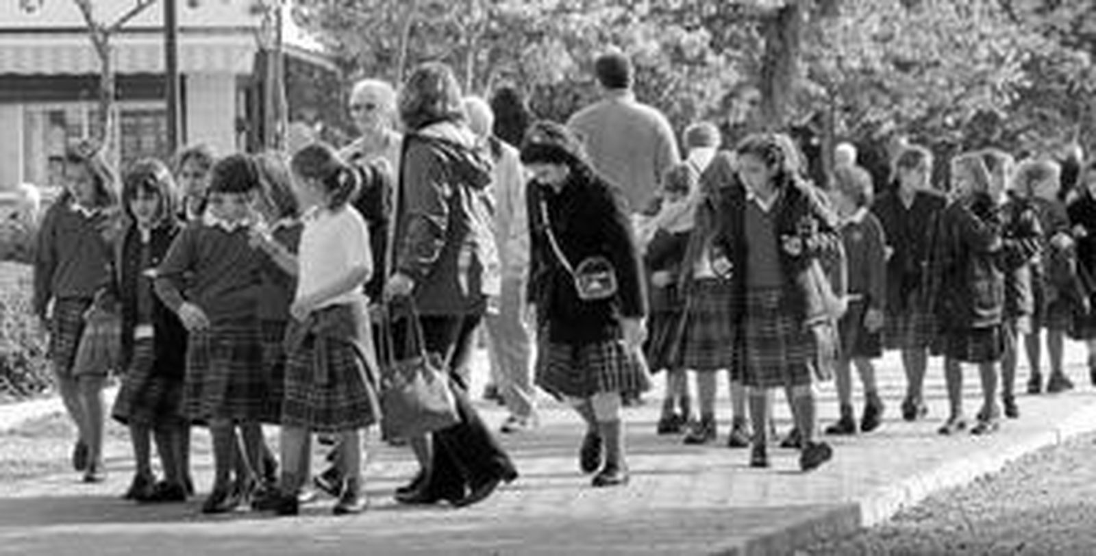 Un grupo de niñas uniformadas camina por una calle de la ciudad.
