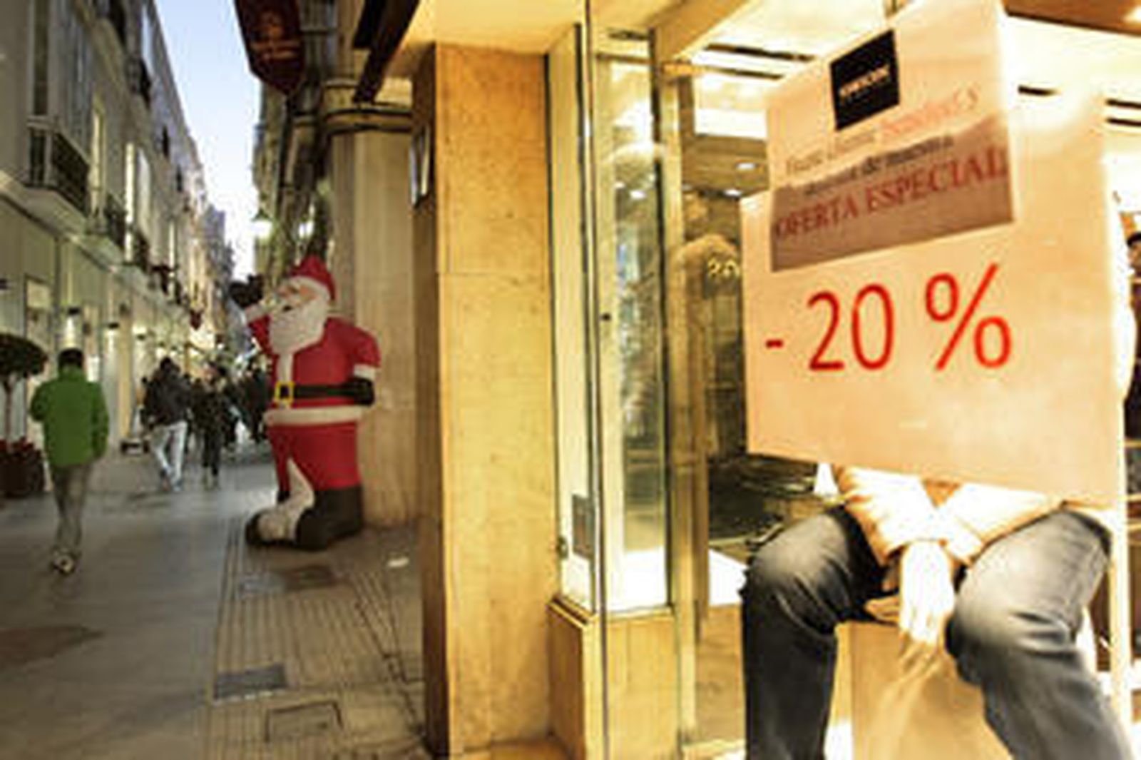 Anuncios de descuento en una tienda de ropa de la calle Columela de Cádiz, con un Papá Noel de fondo como ambientación. /Fito Carreto