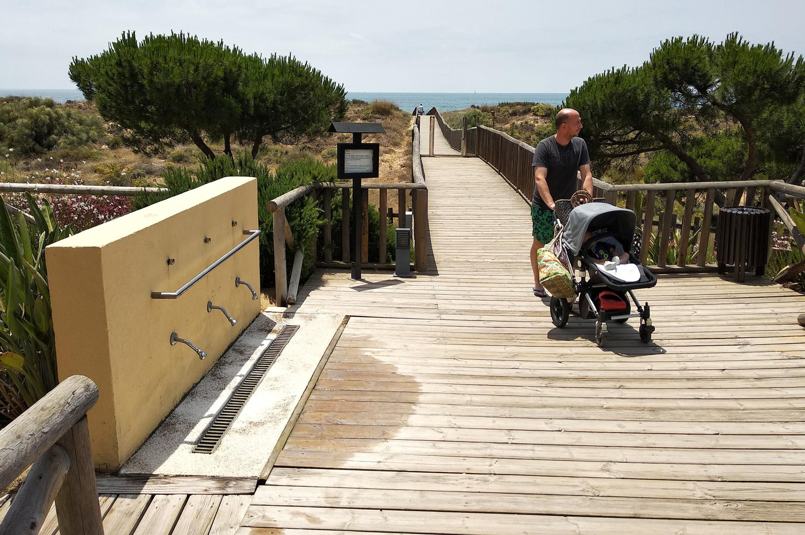 Un turista lleva un carrito de bebé por una de las pasarelas que dan acceso a una playa onubense.