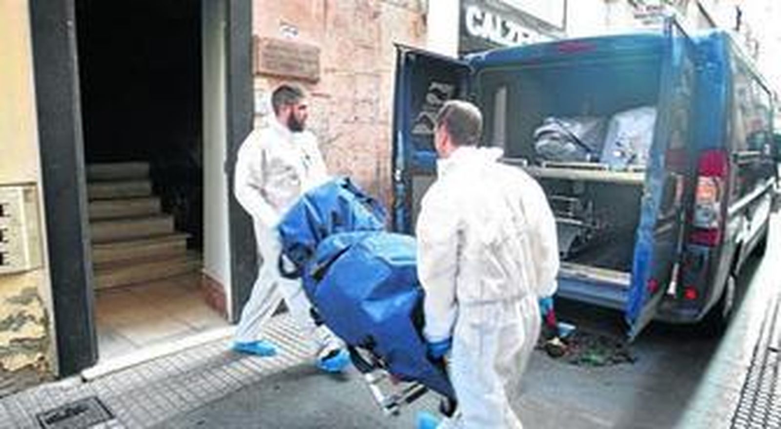 Dos trabajadores de los servicios funerarios realizan el traslado del cadáver el pasado lunes.