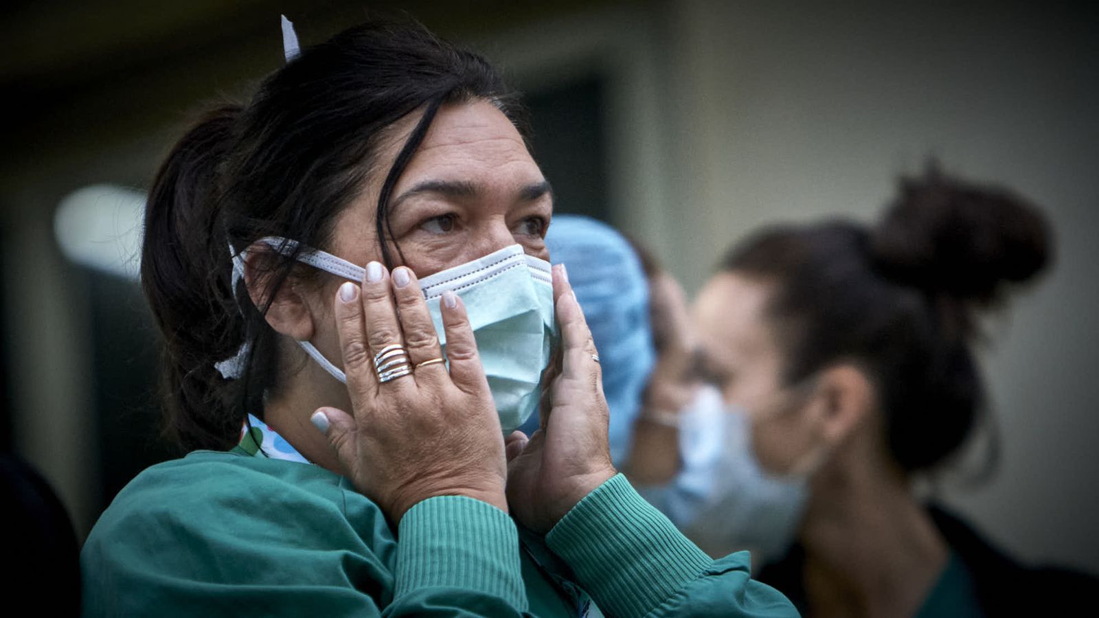 Una mujer se ajusta la mascarilla antes del homenaje diario a los sanitarios.
