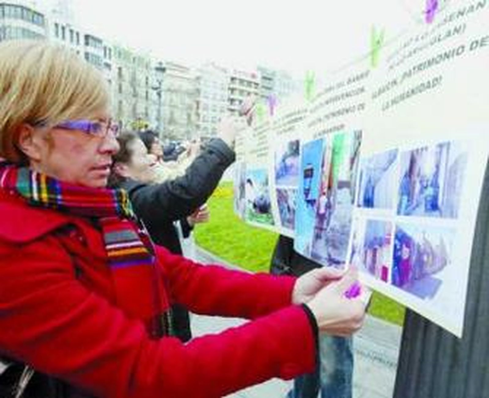 Una vecina pega una de las fotografías en la Fuente de las Batallas.