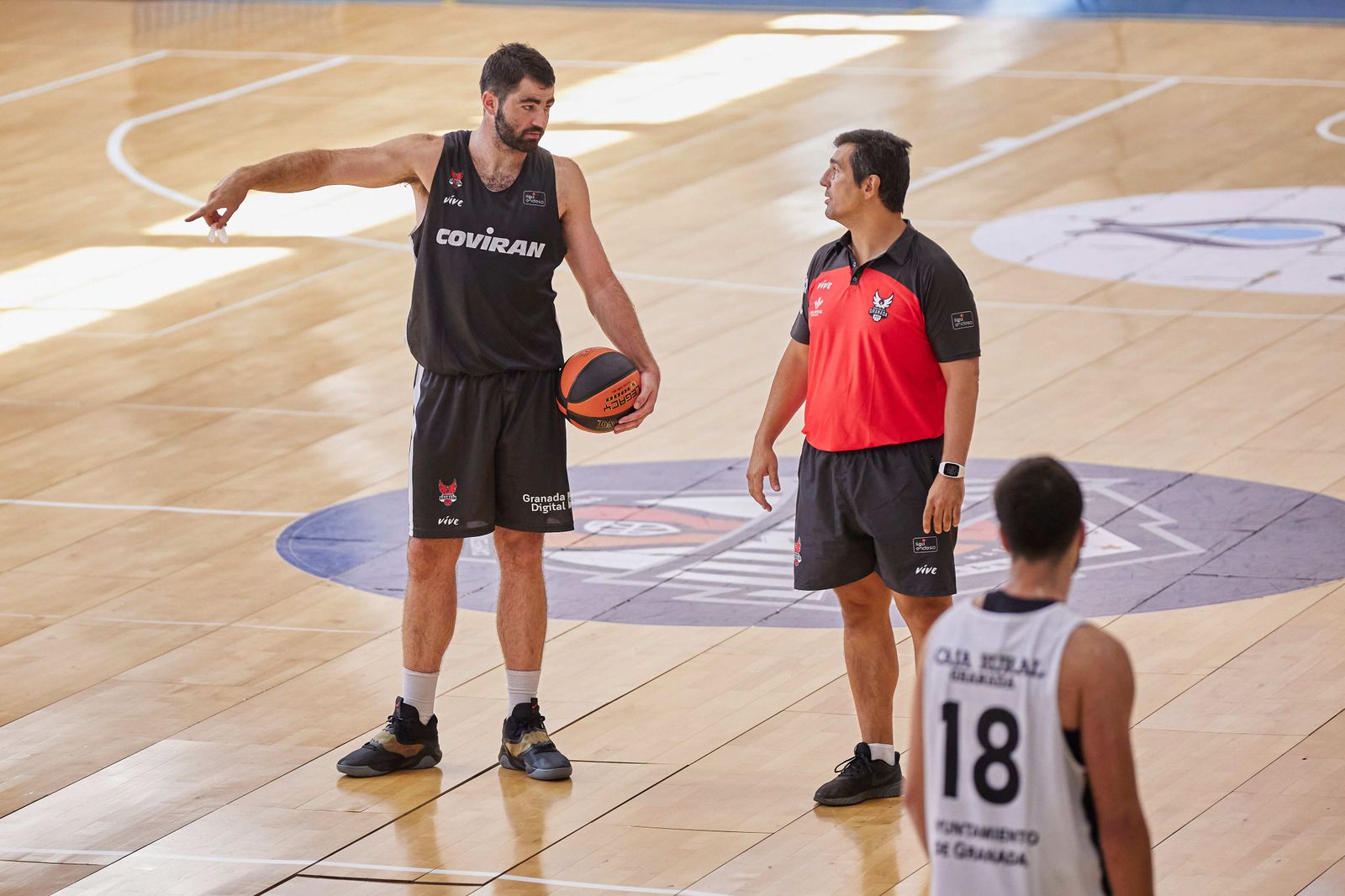Pablo Pin charla con Luke Maye en un entrenamiento en el Pabellón Veleta.