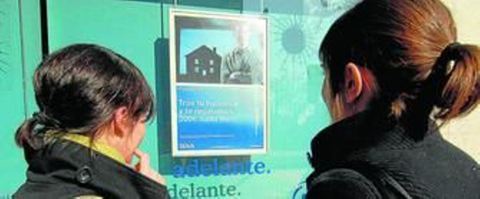 Dos jóvenes observan un anuncio de una entidad financiera.