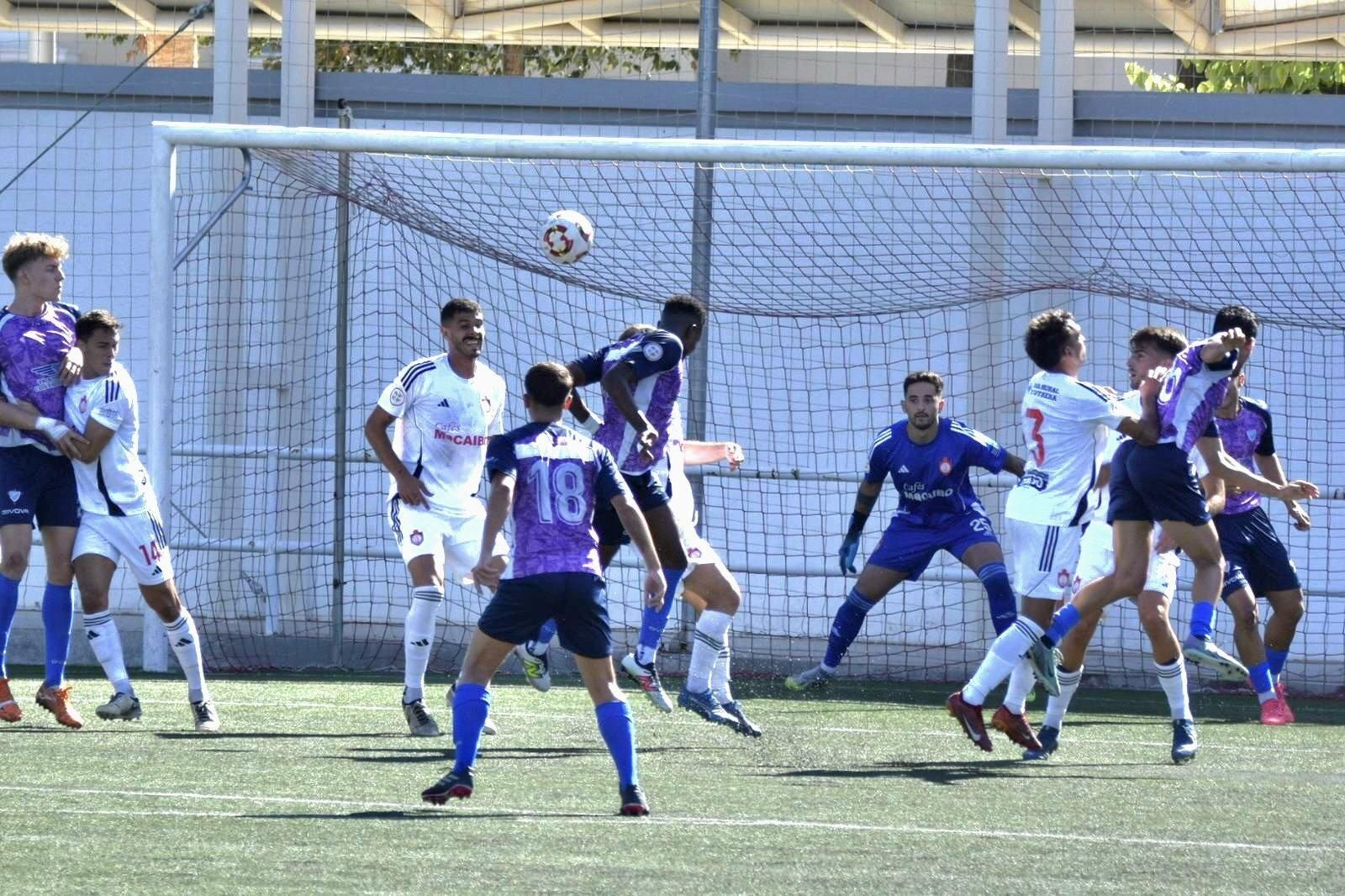 Jugadores del Bollullos saltan a la disputa en un balón parado.