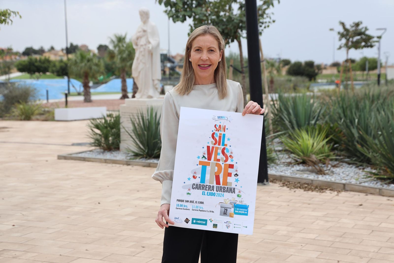La concejal de Deportes, María José Martín, posa sujetando el cartel de la XXXVII Carrera San Silvestre El Ejido.