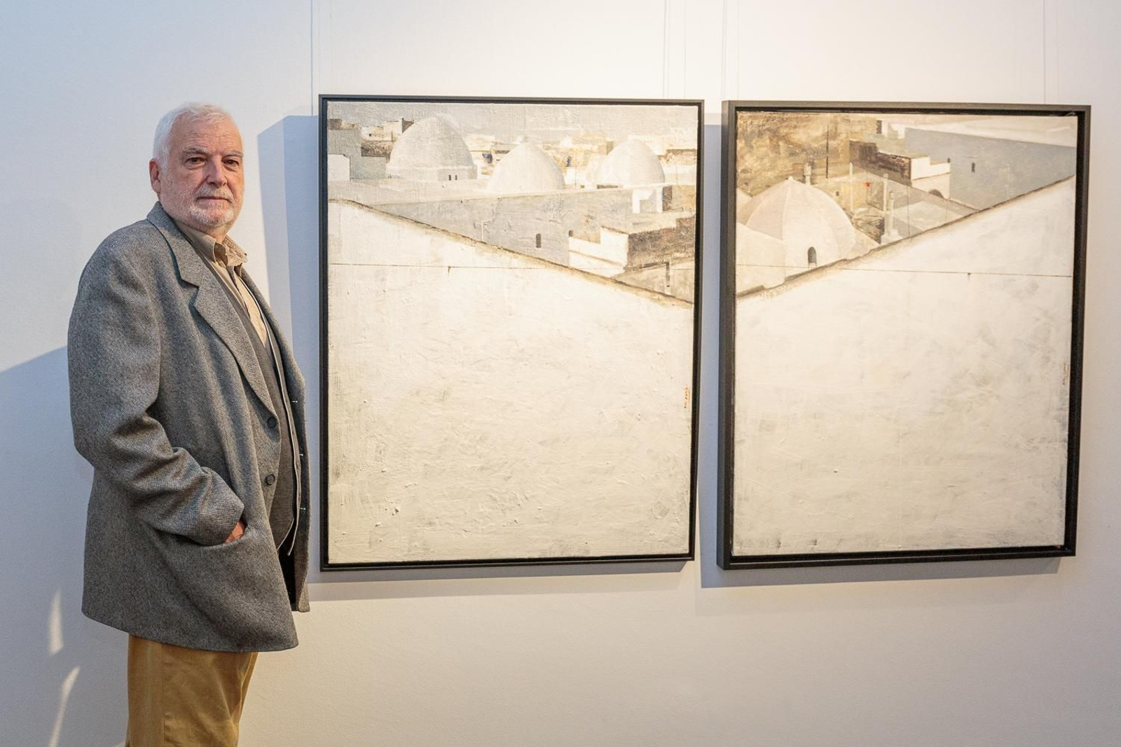 El pintor gaditano Manolo Cano posa ante dos de los cuadros que expone en Sevilla.