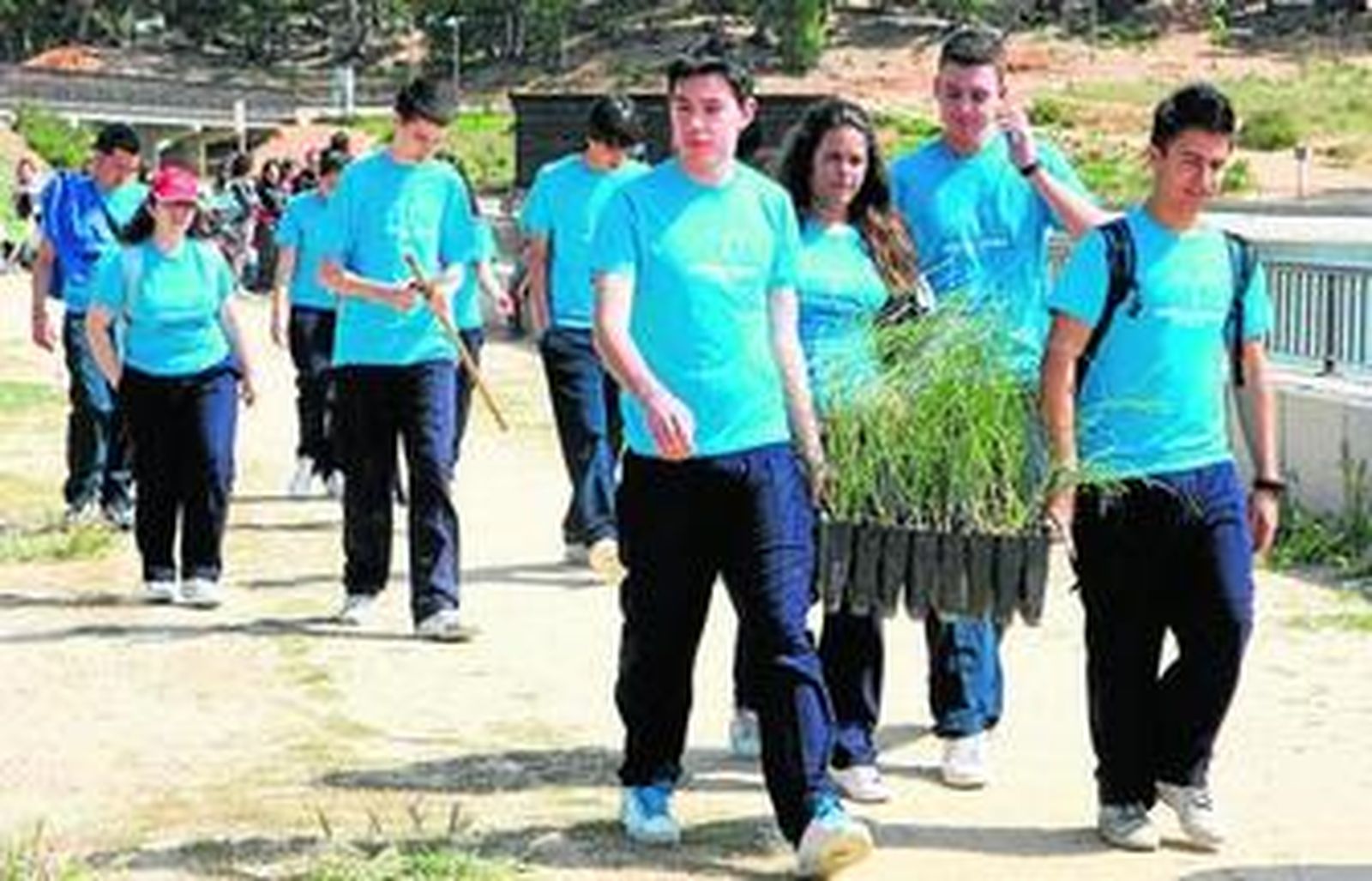 Alumnos del colegio portando los pequeños ejemplares arbóreos que plantaron en el Parque Moret.