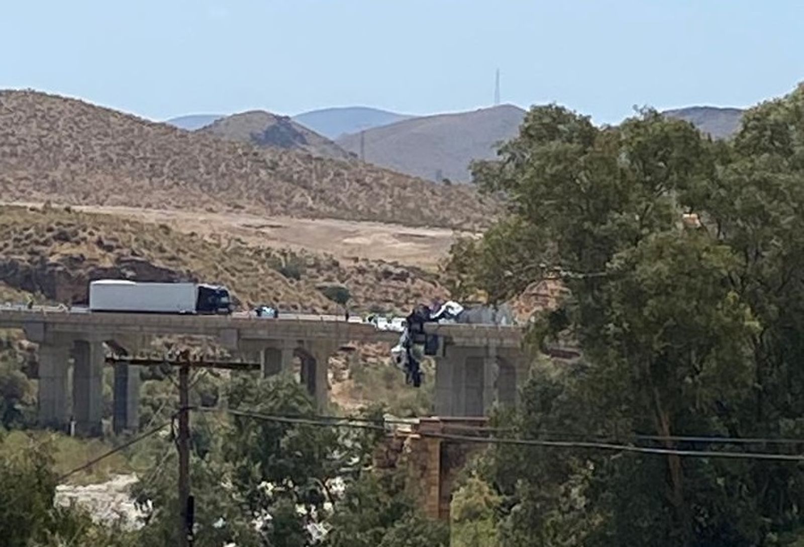 Vista lejana del accidente, con uno de los camiones colgando del puente.