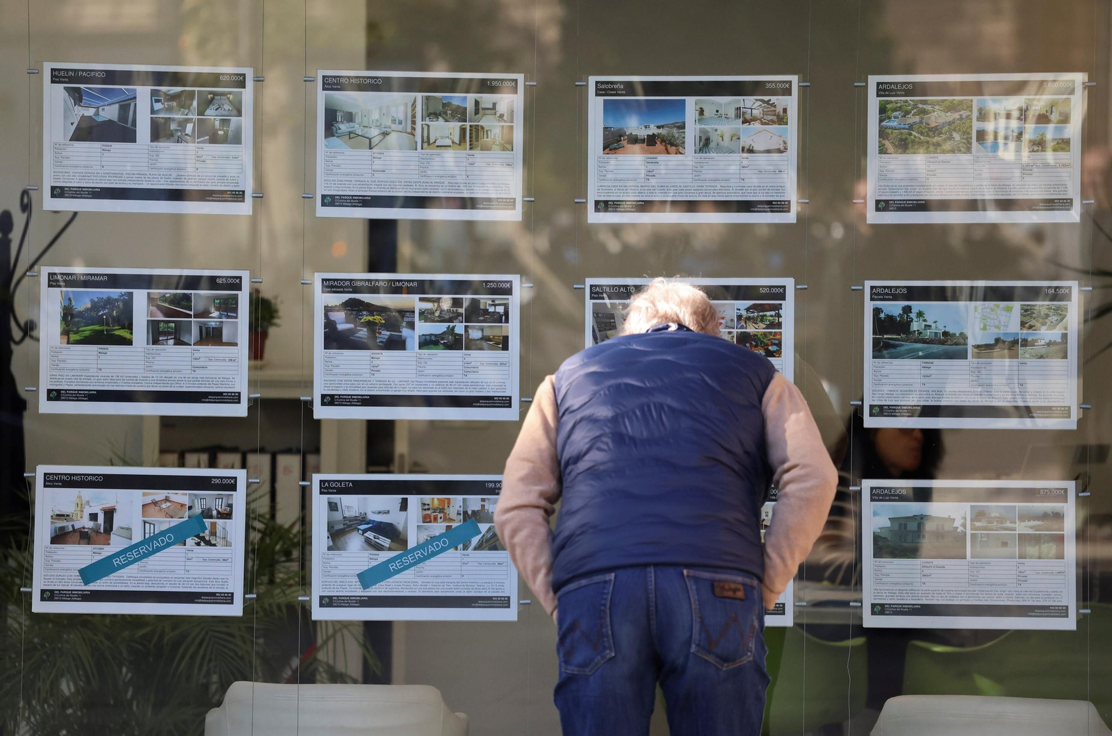 Una persona consulta los precios de la viviendas en el escaparate de una inmobiliria de Málga.