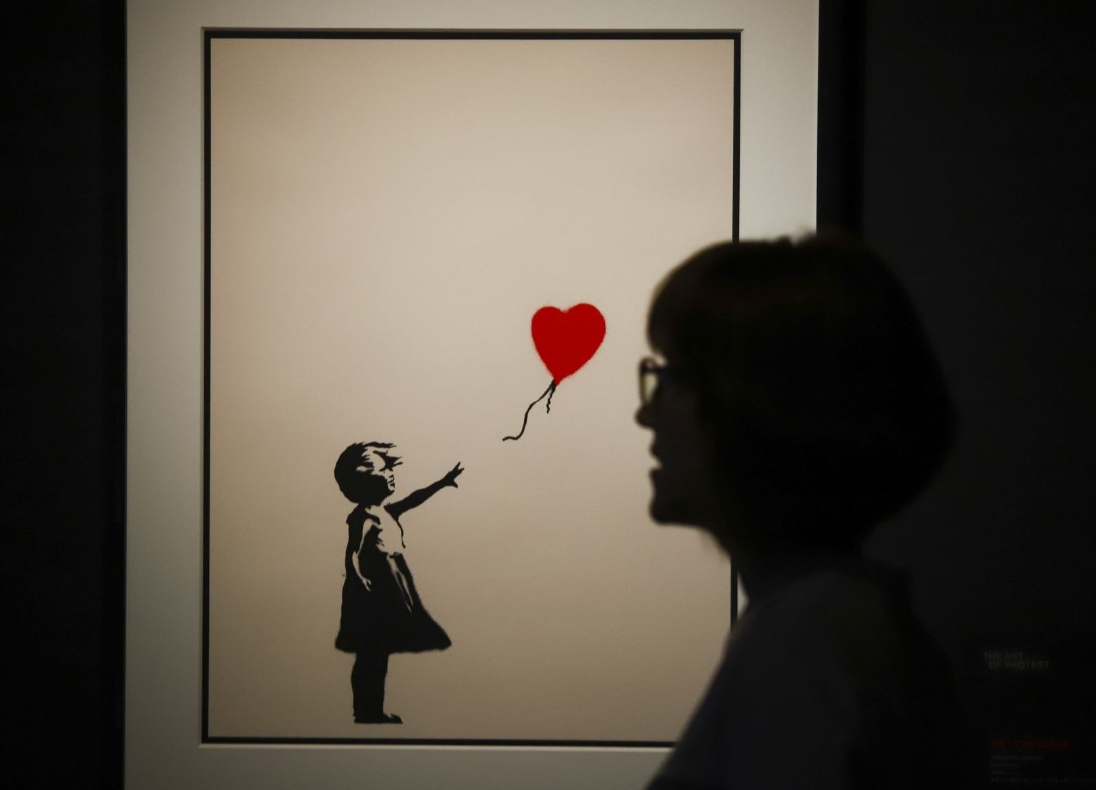Una mujer pasa frente a la obra ‘Niña con globo’ de la exposición 'Banksy. The art of protest’.