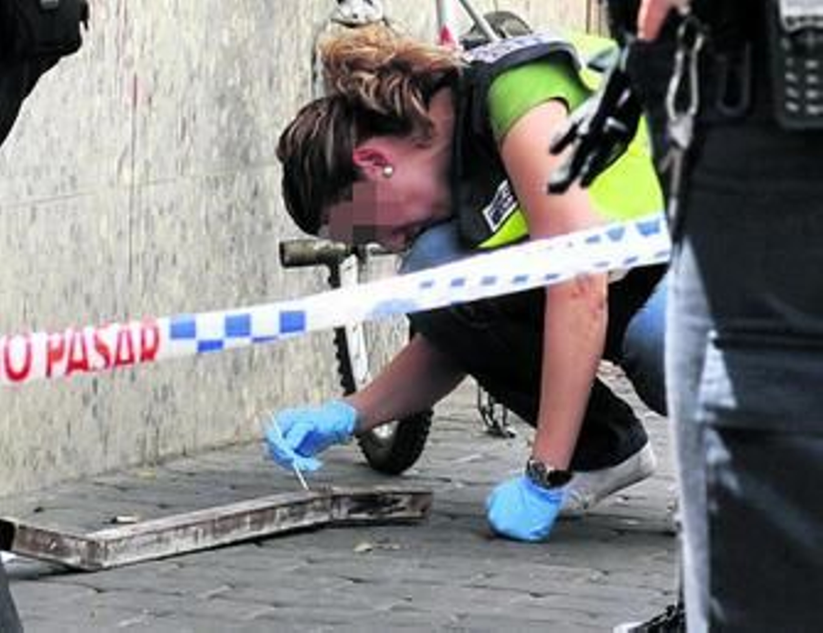 Una agente de la Policía Científica examina la barra utilizada por el menor para destrozar el coche.