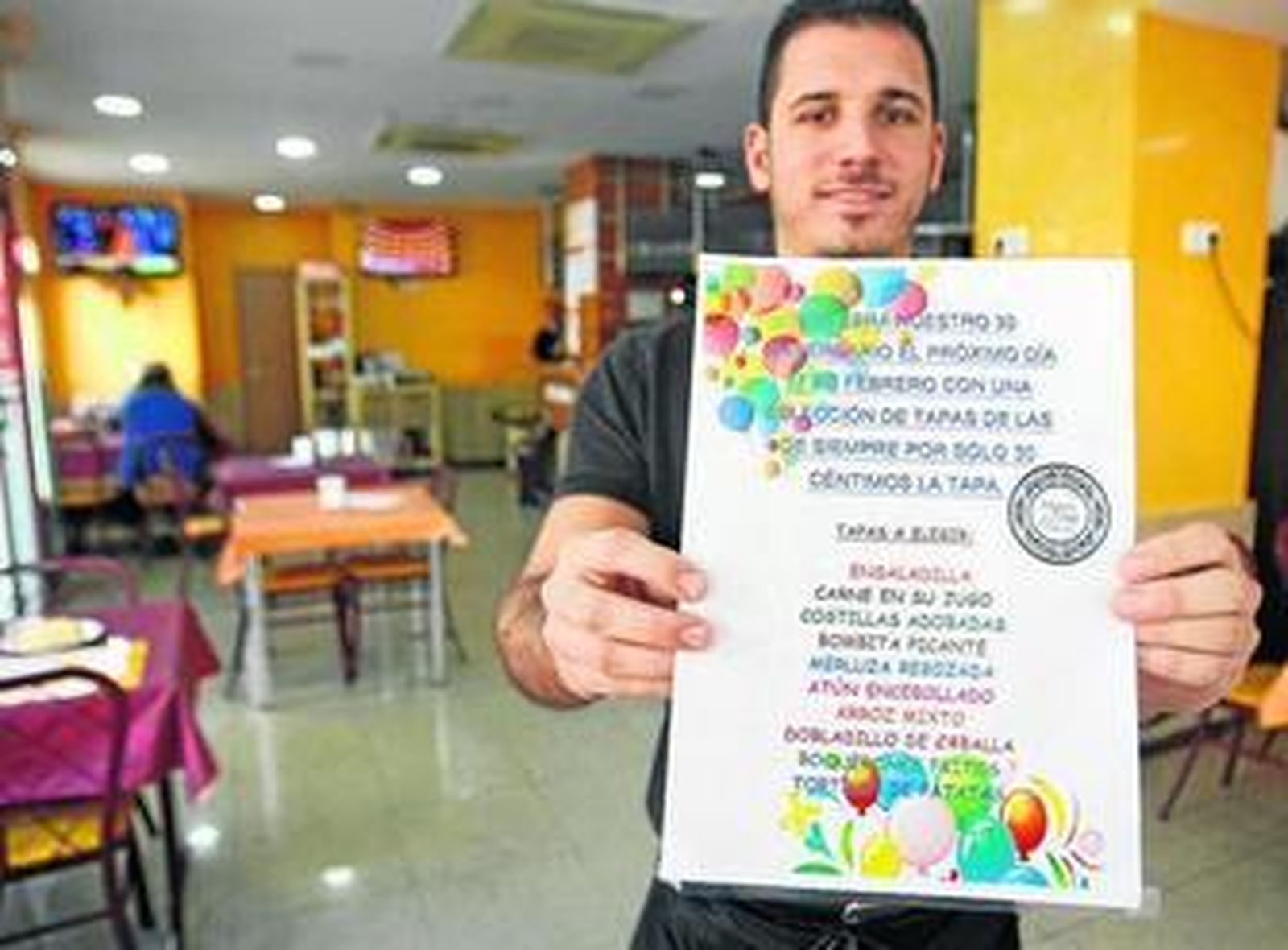 Un camarero sostiene el cartel que anuncia la jornada especial.