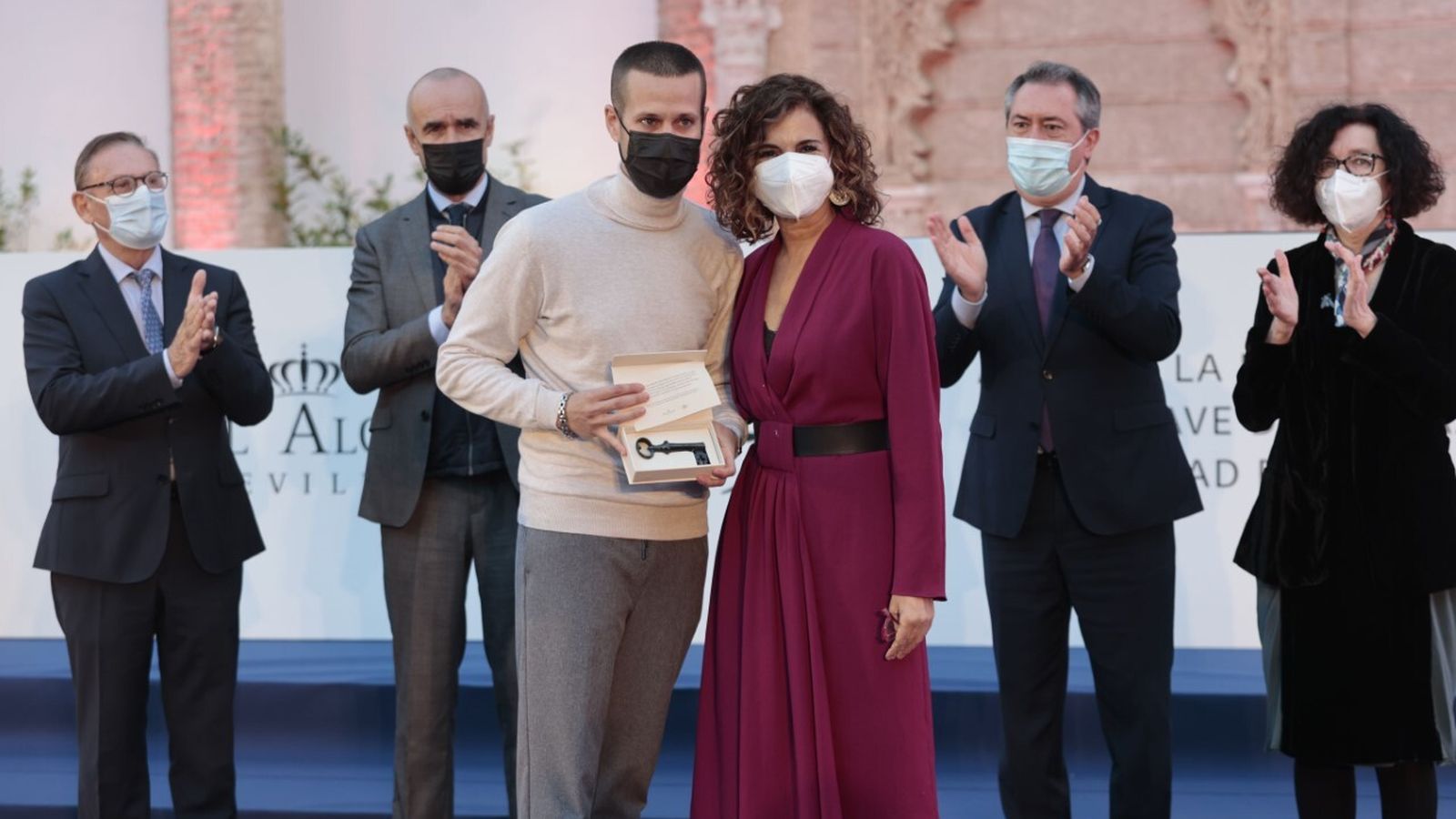 La ministra María Jesús Montero entrega una de las llaves al hijo de un homenajeado en presencia del alcalde, el teniente de alcalde, el alcaide y la directora-conservadora del Alcázar.