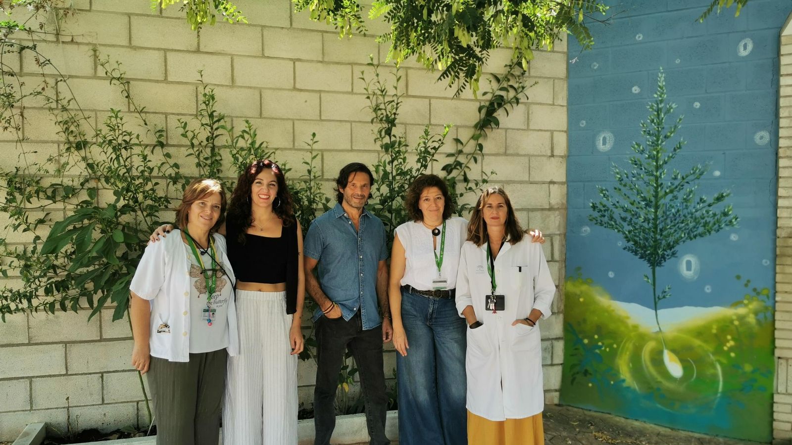 Los muralistas junto a personal sanitario en el patio de la Unidad de Hospitalización de adultos con los murales al fondo.