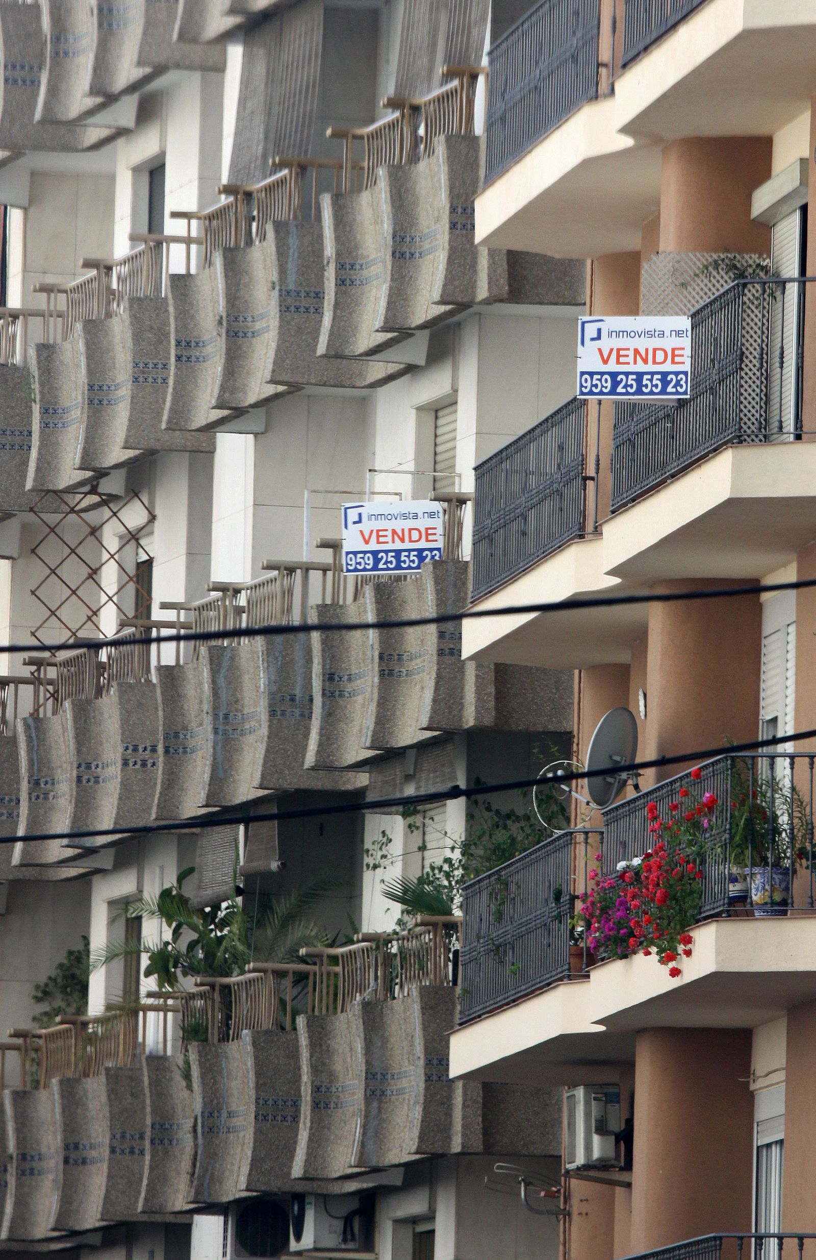 Bloque de viviendas con algunos carteles de venta en los balcones, en una céntrica calle de Huelva.