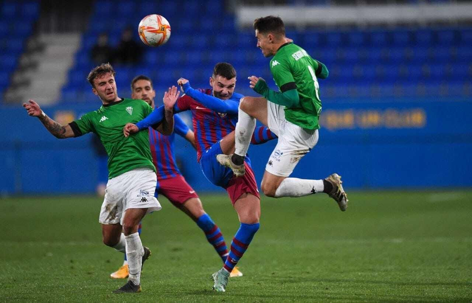 Sergio Cortés despeja una pelota ante un contrario con la ayuda de Juan Agüero.