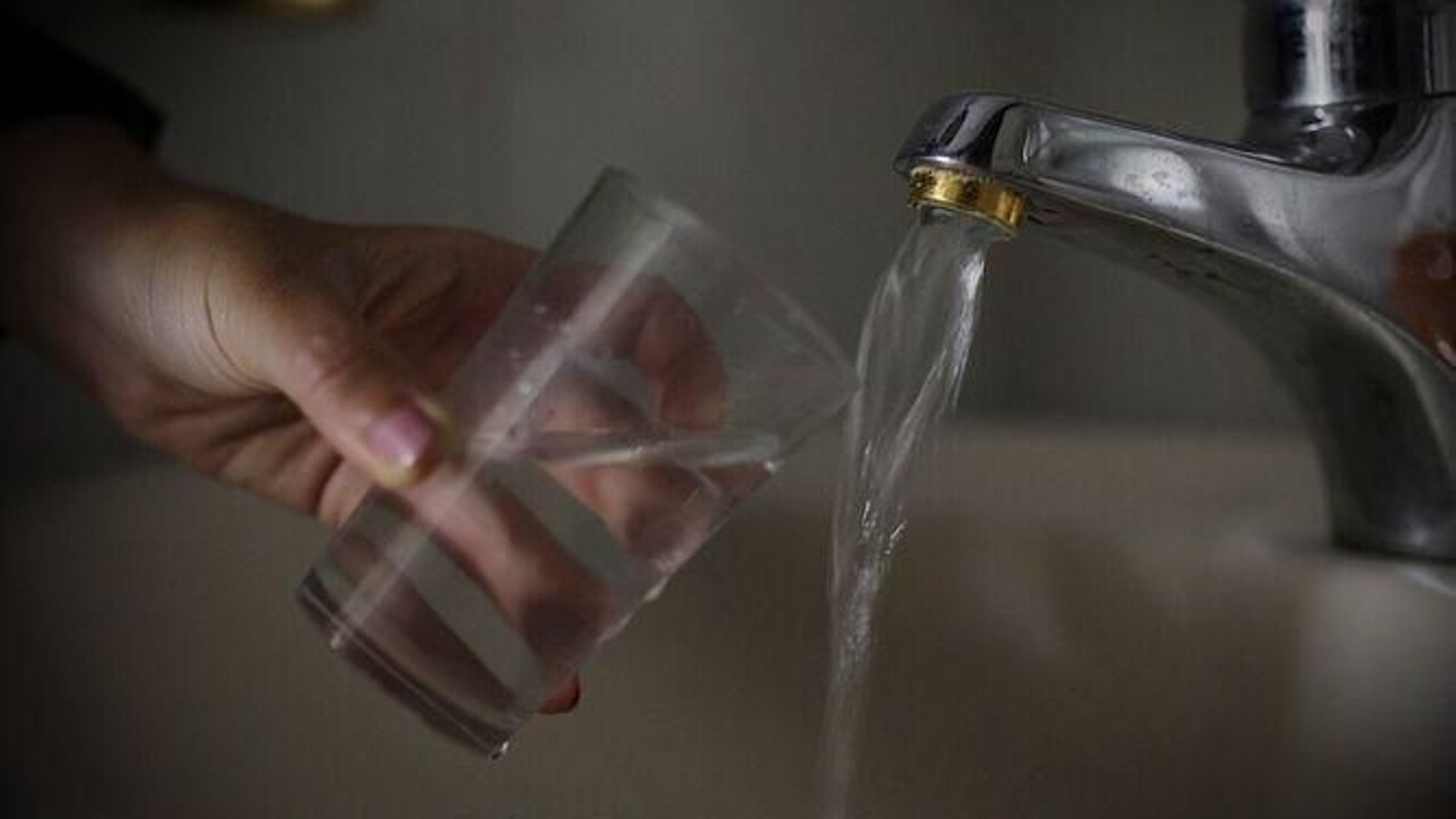 Un usuario llena un vaso de agua en su hogar