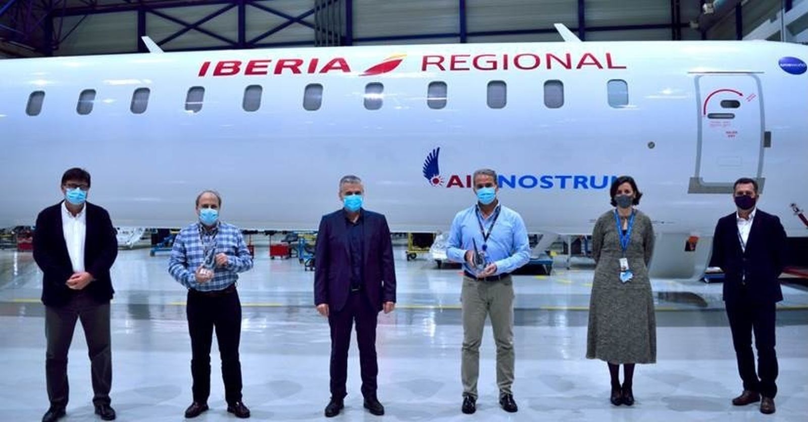 Serge Rosa, representante de MHIRJ, en el centro, flanqueado por Enrique Gómez, jefe de flota de CRJ200, y José Antonio Córdoba, jefe de flota del CRJ900 y CRJ1000, que sostienen los premios, acompañados de Fermín Tirado, Lourdes Beltrán y Jesús Cendán, responsables del Área Técnica, delante de un avión de la compañía. A.M.