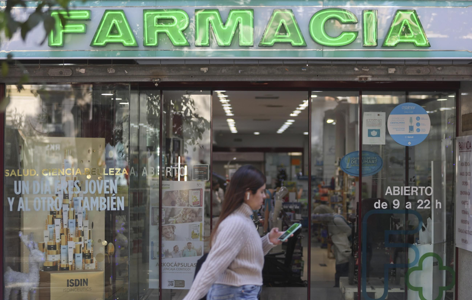 Una mujer pasa por delante de una oficina de farmacia en Málaga.
