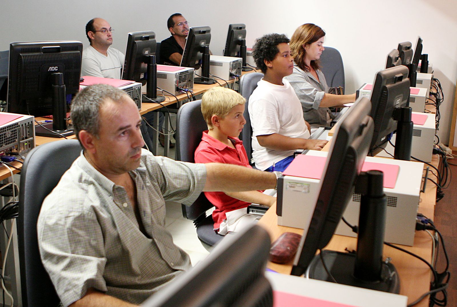 Un grupo de ciudadanos participa en un curso sobre informática en una biblioteca de Huelva.