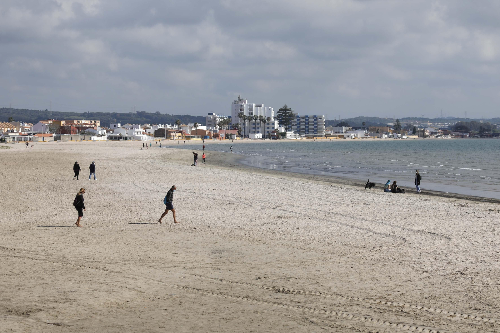 Varias personas pasean por la zona de La Concha, donde se acumula más arena.