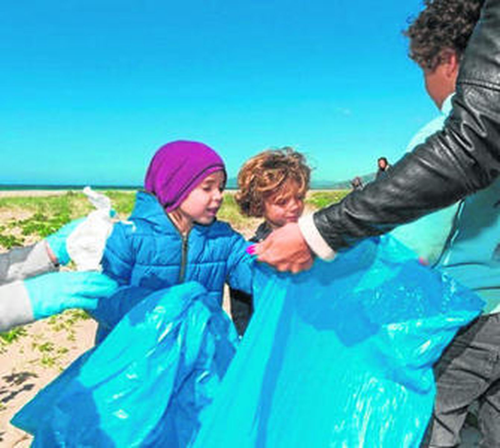 Dos niños recogen bolsas de basura para la limpieza.