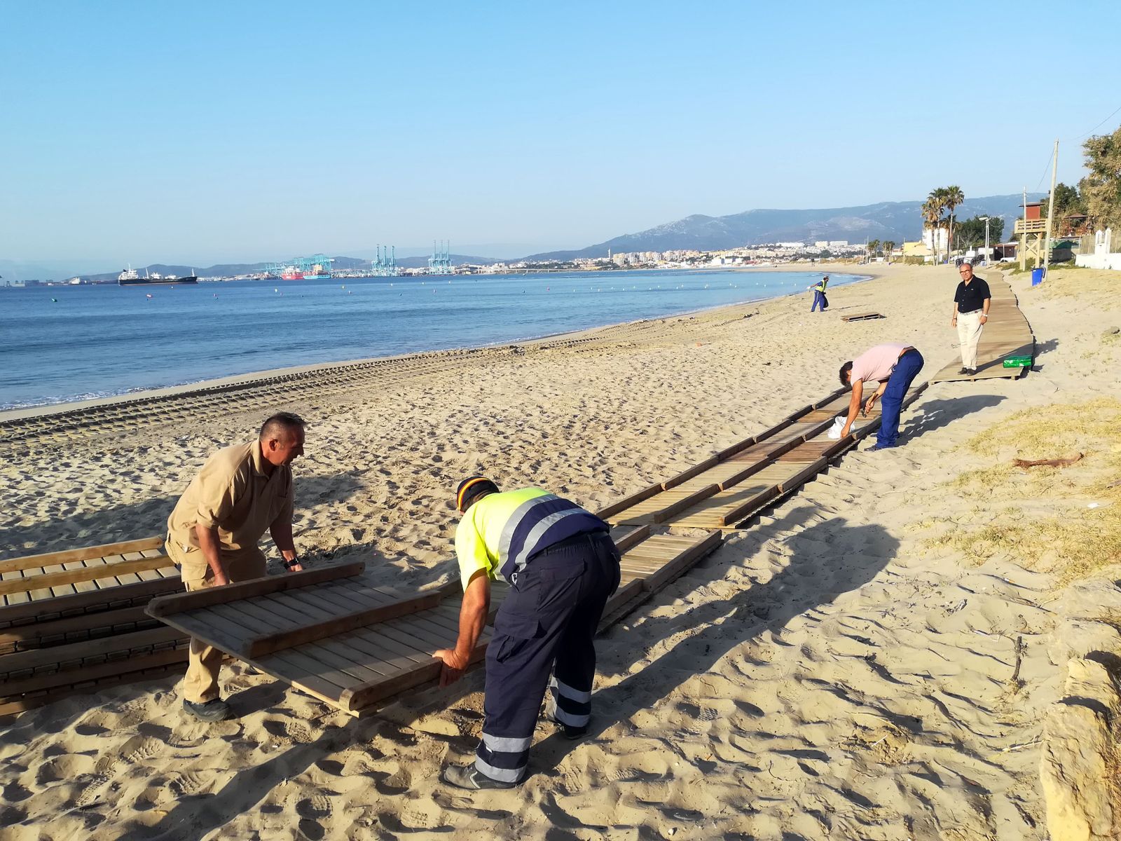 Varios operarios instalan la pasarela en la playa de Palmones, ayer.