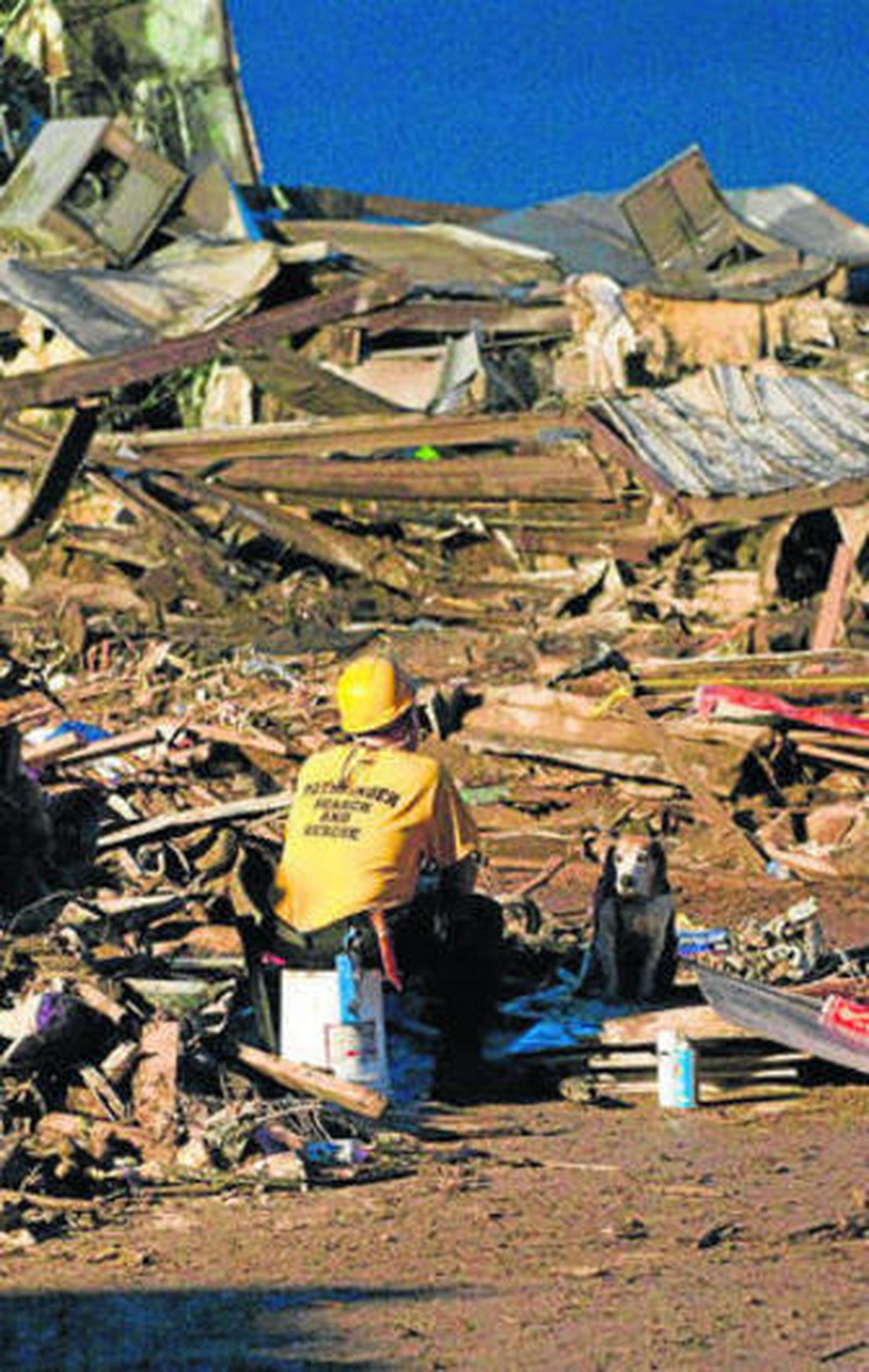 Un miembro de los servicios de rescate sentado ante las ruinas.