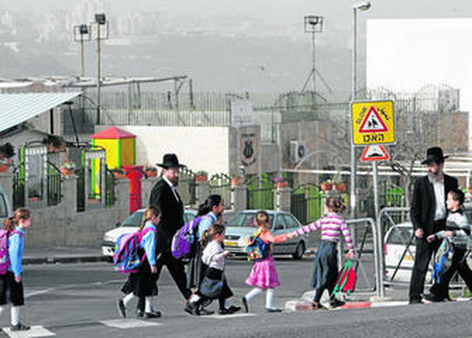 Dos judíos ultraortodoxos acompañan a los niños a la escuela en uno de los asentamientos de Jerusalén.