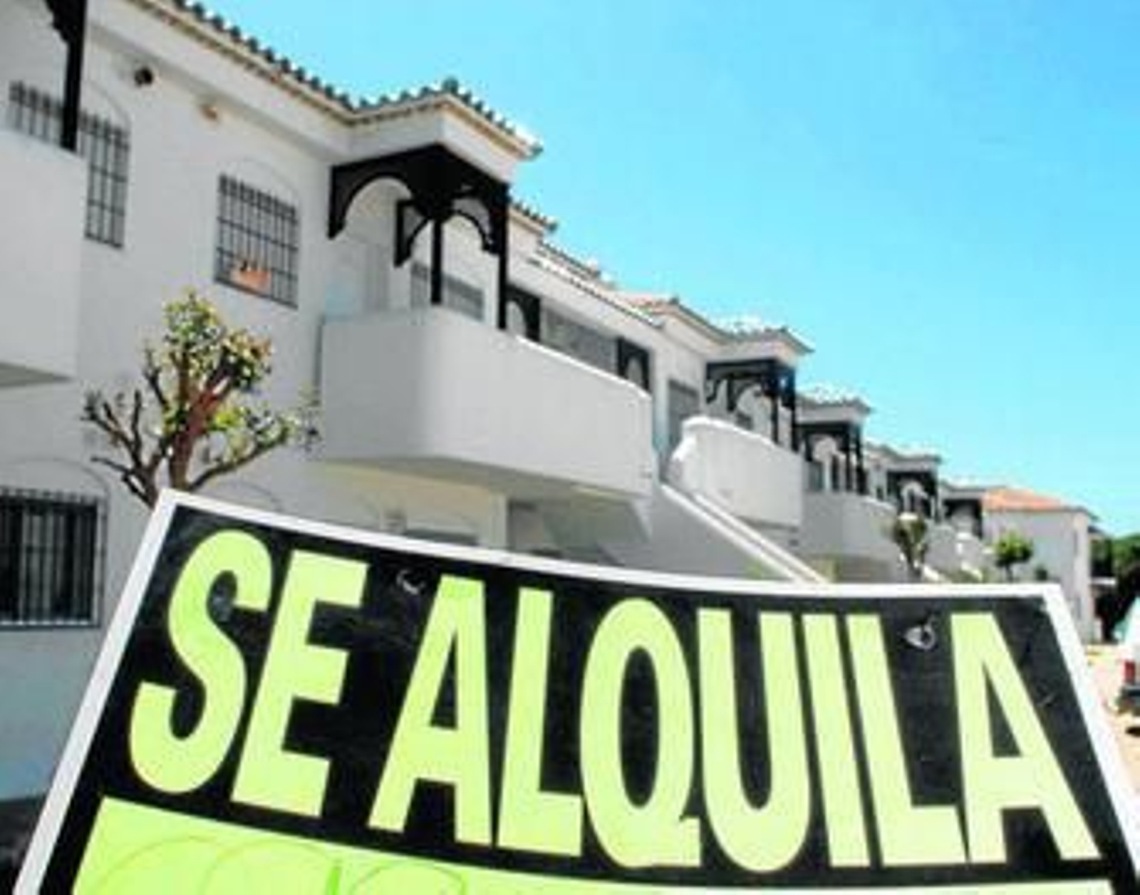 Un cartel de alquiler junto a una promoción de viviendas turísticas en la costa.